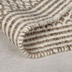 a close up view of a blanket on a bed with white and brown striped fabric