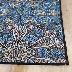 a close up of a blue and black rug on a wooden floor