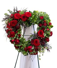 a wreath with red roses and greenery on it