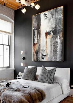 a bedroom with black walls, white bedding and fur rugs on the floor