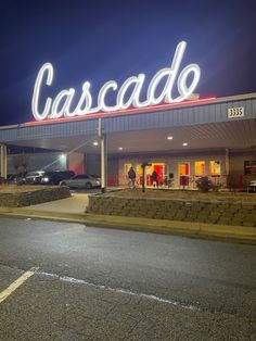 a car dealership at night with the word cascade lit up