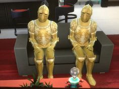 two golden statues sitting on top of a red carpeted floor next to a couch