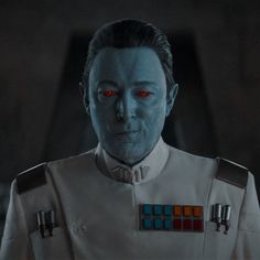 a man with red eyes wearing a star wars uniform in front of a dark background