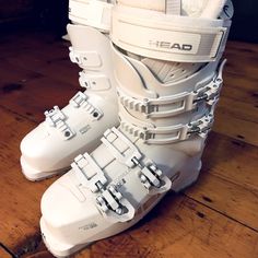 a pair of white ski boots sitting on top of a wooden floor