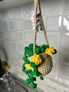 a crocheted bag hanging from a rope with flowers on the front and bottom