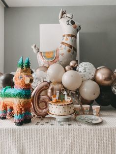 a table topped with lots of balloons and cake next to a giant cat balloon on top of a table