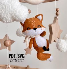 a stuffed fox is hanging from a wooden mobile with stars and clouds in the background