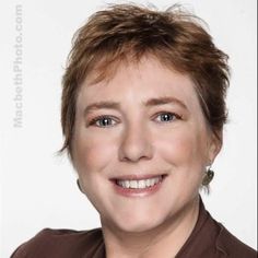 a woman with short brown hair smiling at the camera while wearing a brown shirt and earrings