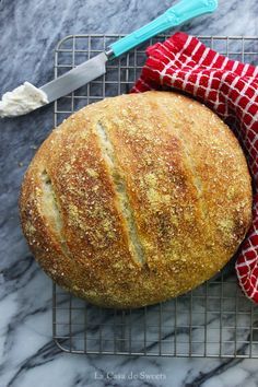 a loaf of bread sitting on top of a cooling rack next to a red and white towel