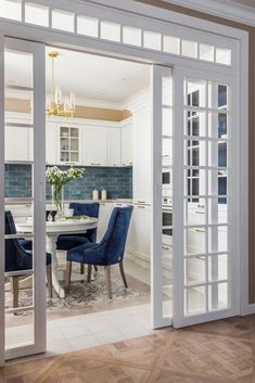 an open door leading to a kitchen with blue chairs and a table in the middle