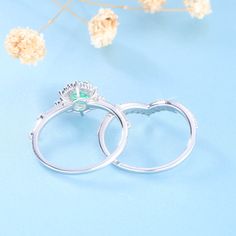 two wedding rings sitting next to each other on top of a blue surface with flowers