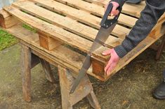 a person holding a large knife on top of a wooden bench