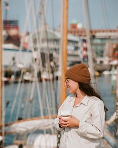 a woman standing next to a boat holding a cup