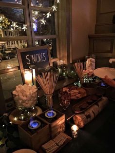 a table filled with candles and food next to a sign that says s'mores