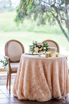 the table is set up with two chairs and a round table covered in a pink blanket