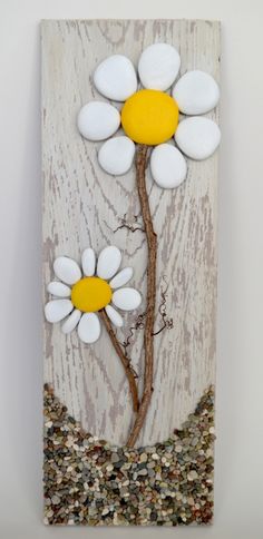 two white flowers with yellow centers on a wood paneled wall hanging from a hook