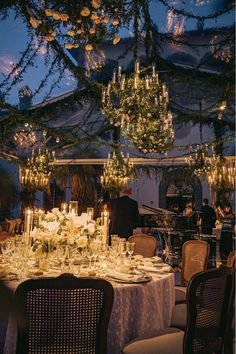 a dining table set up with candles and flowers on it for an elegant dinner party