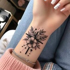 a woman's wrist tattoo with flowers and stars on her left arm, while she is