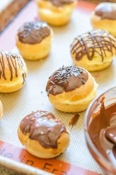 chocolate covered doughnuts sitting on top of a baking sheet