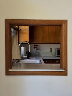 a kitchen with wooden cabinets and white counter tops is reflected in a mirror on the wall