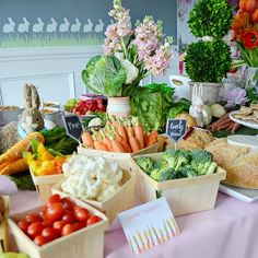 a table filled with lots of different types of food on top of a pink table cloth