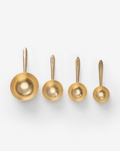 four brass measuring spoons lined up in a row