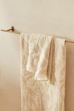 two towels hanging on a towel rack next to a white wall and wooden flooring