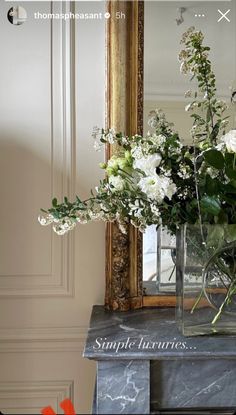 a vase filled with white flowers sitting on top of a table next to a mirror