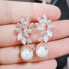 a close up of a person holding a pair of earrings with pearls and crystals on them