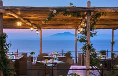 an outdoor dining area overlooking the ocean at dusk