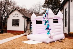 an inflatable bouncer with balloons is on the lawn at bunny hives