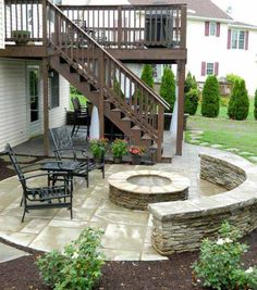 a patio under deck with seating and firepit on the front lawn, as well as stairs