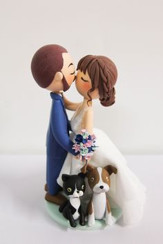 a wedding cake topper with a bride and groom surrounded by dogs on a white background