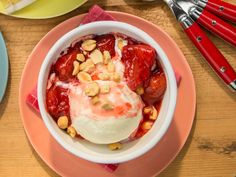 a bowl filled with fruit and nuts on top of a pink plate next to other plates