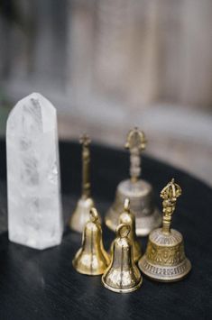 three brass bell figurines sitting on top of a table next to a crystal