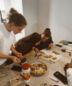 three people sitting at a table with food on it