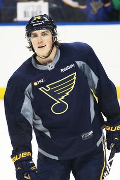 a hockey player is standing on the ice with his hands in his pockets and looking at the camera