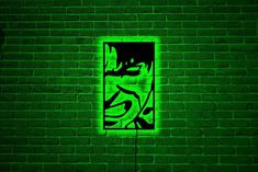 a green brick wall with graffiti on it and a square window in the middle that is lit up