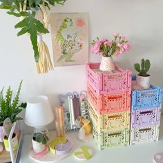 there are many different colored boxes on the table with flowers in vases next to them