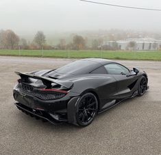 a black sports car parked in a parking lot on a foggy day with no one around