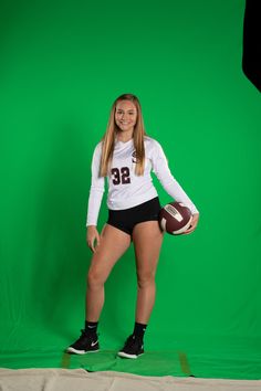 a female football player is posing for a photo in front of a green screen background