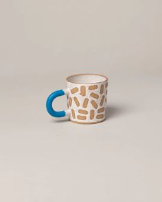 a giraffe print coffee cup with blue handles on a grey background, sitting in front of the camera