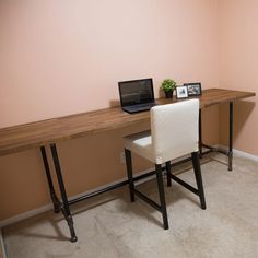 a laptop computer sitting on top of a wooden desk next to a white chair in a room