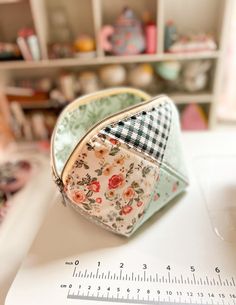 a small purse sitting on top of a white table next to a ruler and other items