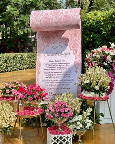 pink and white flowers are sitting on small tables in front of a sign that says,