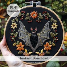 a hand holding up a black bat with flowers on it and the words instant embroidery pattern