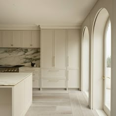 a large kitchen with white cabinets and marble counter tops, along with arched doorways