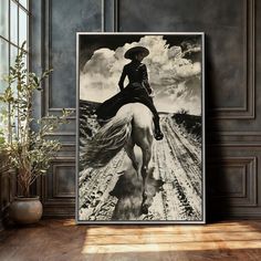 a black and white photo of a woman riding a horse on a dirt road with clouds in the background