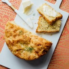 bread and butter are sitting on a cutting board with utensils next to it