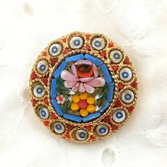 a colorful brooch with flowers on it sitting on top of a white tablecloth